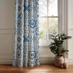 May include: A patterned curtain with a blue and white geometric design hangs next to a window. The curtain features a repeating pattern of star and floral shapes. A potted plant sits on the floor near the window.
