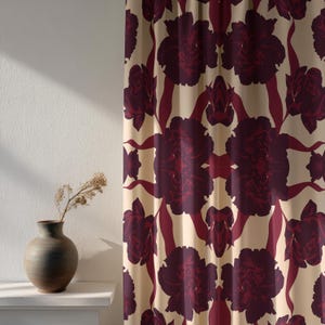 Könnte beinhalten: Cremefarbener Vorhang mit einem sich wiederholenden Muster aus großen, stilisierten burgunderfarbenen Blumen und Stielen. Das florale Design erzeugt eine symmetrische, auffällige Darstellung. Der Vorhang hängt vor einer weißen Wand.