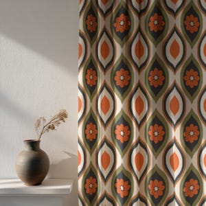 May include: A patterned curtain with a retro design. The fabric features a repeating pattern of orange flowers and teardrop shapes in shades of orange, green, grey, and cream. The curtain is hanging in front of a white wall.