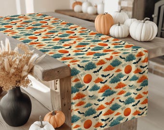May include: A Halloween-themed table runner featuring a repeating pattern of orange suns, blue and orange clouds, and black bats on a cream background. The runner is displayed on a wooden table, with pumpkins and decorative elements.