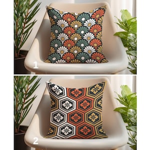 May include: Two decorative cushions with Japanese-inspired patterns. The top cushion has a floral design in white, orange, green, and black. The bottom cushion has a geometric pattern in black, orange, and yellow.