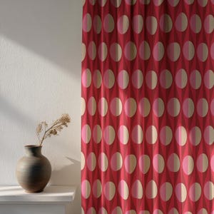 May include: Red curtain featuring a repeating pattern of half-circles in alternating pink and beige tones. The curtain has a geometric design with diamond shapes in the background. A dark vase with dried flowers sits on a white shelf.