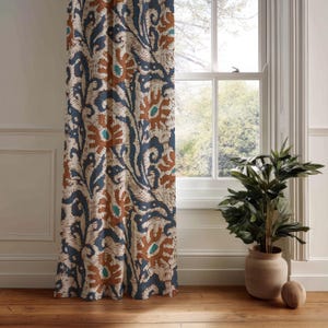 Könnte beinhalten: Gemusterter Vorhang mit einem sich wiederholenden Design aus braunen, blauen und türkisfarbenen Blumenformen auf cremefarbenem Hintergrund. Der Vorhang hängt vor einem Fenster, mit einer Topfpflanze im Vordergrund.