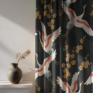 Può includere: Tenda nera con un motivo ripetuto di gru bianche, rosse e verdi in volo, intervallate da accenti floreali dorati. Il design è ambientato su uno sfondo scuro, creando un contrasto sorprendente. La tenda è appesa davanti a un muro bianco.