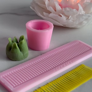 Może przedstawiać: Zestaw trzech ceramicznych kubków z nakrapianym, matowym wykończeniem. Kubki są w odcieniach kremu, jasnoszarości i ciemnoszarości. Każdy kubek ma prosty, minimalistyczny design i zaokrąglony uchwyt.