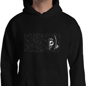 Op de afbeelding: Zwart hoodie met een wit grafisch ontwerp van een gezicht met een patroon van stippen op de achtergrond.