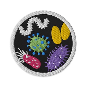 Può includere: Una toppa rotonda ricamata con un bordo bianco e uno sfondo nero. La toppa presenta vari microbi colorati, tra cui un virus verde, un batterio viola, un'ameba rosa, un ovale giallo e un verme bianco.