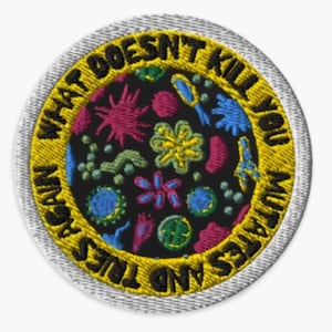 May include: A yellow and white embroidered patch with the text "What doesn't kill you makes you stronger and tries again" in black. The patch features a black background with colorful embroidered microbes.
