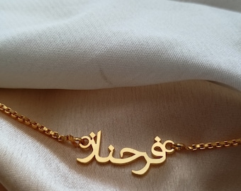 May include: A gold necklace with a nameplate pendant featuring the Arabic word "فوزان" in a cursive script.