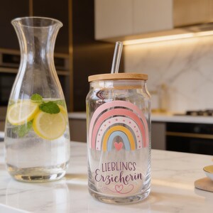 May include: A clear glass tumbler with a bamboo lid and a glass straw, featuring a colorful rainbow graphic and the text "LIEBLINGS Erzieherin" with a small heart icon. The design includes pastel pink, yellow, and blue arches.