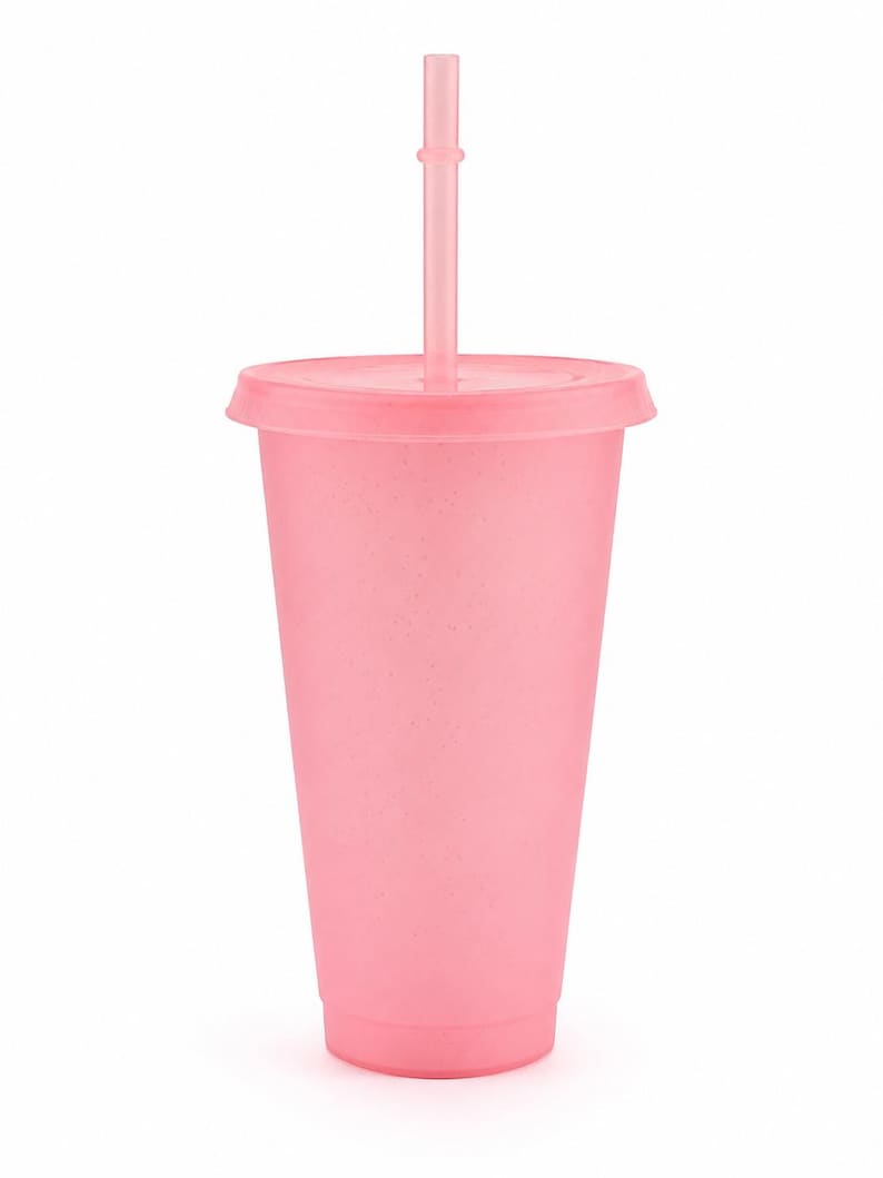 Puede incluir: Un vaso de color rosa claro con un acabado mate y moteado, que incluye una tapa a juego y una pajita recta insertada en el centro. El vaso tiene una forma cil&iacute;ndrica c&oacute;nica con una base plana y un borde ancho, de un color pastel uniforme.