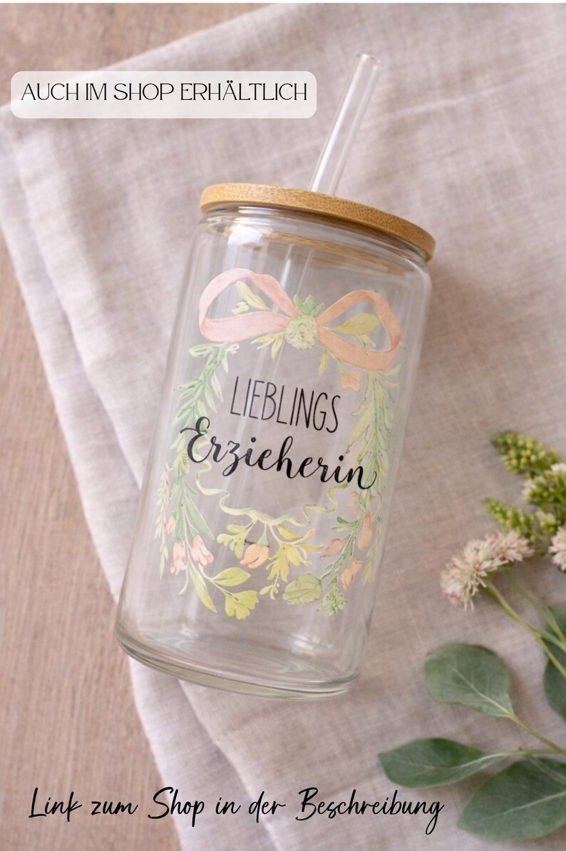 Op de afbeelding: Een doorzichtig drinkglas met een bamboe deksel en een glazen rietje. Het glas is voorzien van een geprinte bloemenkrans in zachte pasteltinten, rondom de zwarte tekst "LIEBLINGS Erzieherin" in een combinatie van schreef- en schrijfletters.