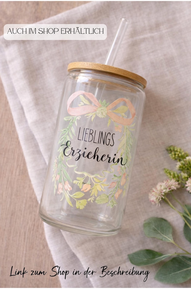 Pode incluir: Um copo de vidro transparente com tampa de bambu e canudo de vidro. O vidro apresenta um design de coroa floral em estilo aquarela em tons de rosa e verde, com o texto em alem&atilde;o "LIEBLINGS Erzieherin" impresso no centro da coroa.