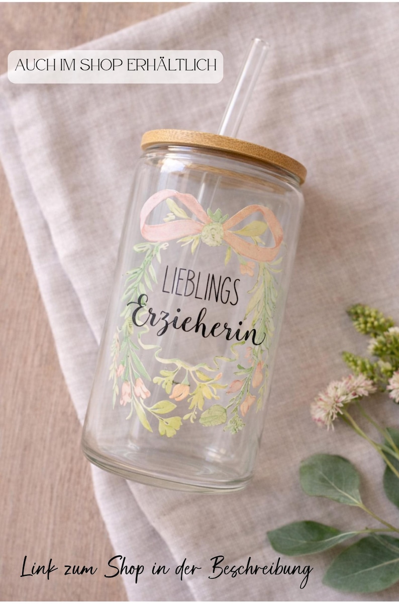 May include: A clear glass tumbler with a wooden lid and a straw. The tumbler features a floral design with the words "LIEBLINGS Erzieherin" and the text "Auch im Shop erh&auml;ltlich" and "Link zum Shop in der Beschreibung".