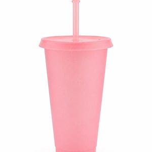 Puede incluir: Un vaso de color rosa claro con un acabado mate y moteado, que incluye una tapa a juego y una pajita recta insertada en el centro. El vaso tiene una forma cil&iacute;ndrica c&oacute;nica con una base plana y un borde ancho, de un color pastel uniforme.