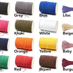 May include: A collection of spools of elastic cord in various colors, including black, grey, blue, lilac, pink, khaki, white, beige, navy, orange, yellow, baby pink, green, red, brown, and burgundy. Each spool is labeled with its color.