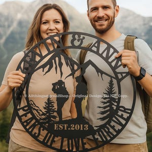 May include: Black metal wall art featuring a mountain scene with the words "Peaks of Love Forever" and "& Anna", with the year "EST.2013". The art includes silhouettes of people, trees, and mountains.