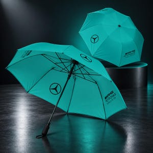 Könnte beinhalten: Zwei türkisfarbene Regenschirme mit dem schwarzen Mercedes-Benz Stern-Logo und dem Schriftzug AMG Petronas Formula One Team. Ein Schirm ist geöffnet und zeigt das schwarze Metallgestell sowie den Griff, der andere ist geschlossen.