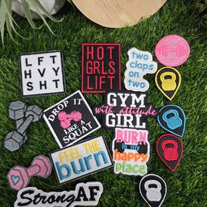 May include: A collection of embroidered patches featuring fitness-themed designs, including dumbbells, kettlebells, and text such as "LFT HVY SHT," "HOT GRLS LIFT," "two claps on two," "DROP IT LIKE A SQUAT," "GYM GIRL," "BURN is my happy place," "FEEL THE burn," and "StrongAF."