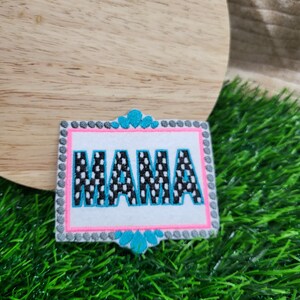 May include: A white patch with black polka dots and the word "MAMA" embroidered in blue with a pink and gray border.