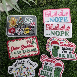May include: A collection of six rectangular and shaped embroidered patches featuring holiday themes. Designs include a gingerbread man, Christmas tree, candy cane, a letter to Santa, Christmas lights, and pickles wearing Santa hats with text.