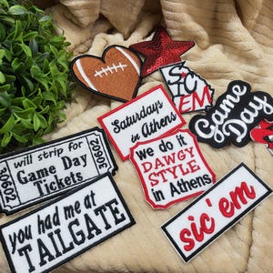 May include: A collection of nine embroidered patches featuring various college football themes. The patches are white, red, and black with text that reads "Game Day", "Saturdays in Athens", "We do it Dawgy Style in Athens", "Sic 'em", and "You had me at Tailgate".