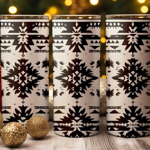 May include: Three white insulated tumblers with a black geometric pattern. The design features symmetrical shapes and lines. The tumblers are displayed with gold and red Christmas ornaments, suggesting a holiday theme.