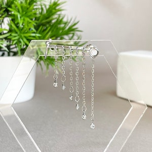 May include: Silver dangle earring with a single clear stone at the top and multiple smaller clear stones dangling from chains.