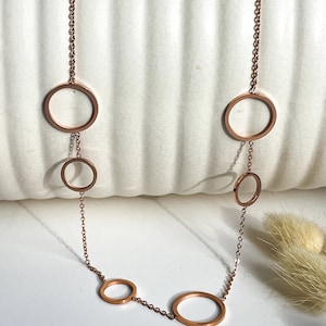May include: A rose gold necklace with a chain and five connected circles of varying sizes.