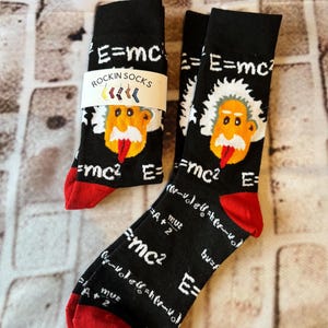May include: Black socks with red heels and toes, featuring a cartoon image of Albert Einstein and the equation E=mc². The socks also have the text "ROCKIN SOCKS" and mathematical formulas.