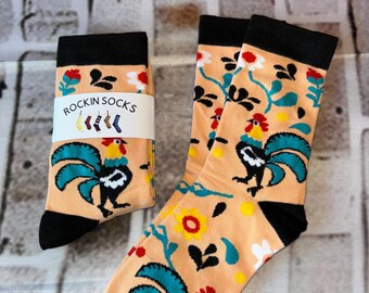 May include: A pair of socks with a peach background and a rooster design. The socks have a black cuff and a white floral pattern. The socks are labelled "Rockin Socks".