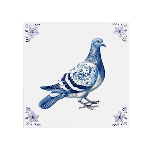 May include: A blue and white ceramic tile with a blue and white pigeon with a floral pattern on its wings. The tile is decorated with four small blue and white flowers in the corners.