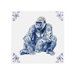 Könnte beinhalten: Quadratische Keramikfliese mit einem sitzenden Gorilla mit detaillierten blauen Blumentattoos. Der Gorilla ist in Blau- und Grautönen dargestellt. Die Fliese hat einen weißen Hintergrund mit blauen floralen Eckakzenten.