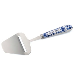 Może przedstawiać: Tarka do sera ze stali nierdzewnej z biało-niebieskim ceramicznym uchwytem. Uchwyt zdobi tradycyjny holenderski wzór Delft blue z nadrukiem słowa "HOLLAND".