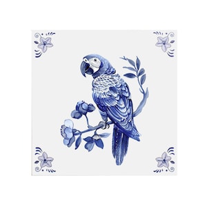 May include: Blue and white ceramic tile featuring a blue parrot perched on a branch with blue flowers. The tile has a white background.
