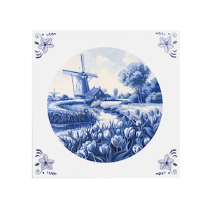 Può includere: Piastrella quadrata in ceramica bianca con un'illustrazione blu e bianca di un paesaggio olandese. La scena comprende un mulino a vento, case, un fiume e tulipani. Accenti floreali decorativi agli angoli.