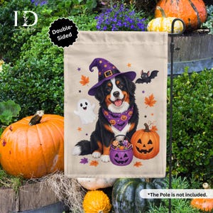 May include: A beige garden flag featuring a Bernese Mountain Dog wearing a purple witch hat and a purple patterned bandana. The dog sits next to a jack-o'-lantern and a ghost, holding a purple pumpkin bucket filled with candy, surrounded by bats.