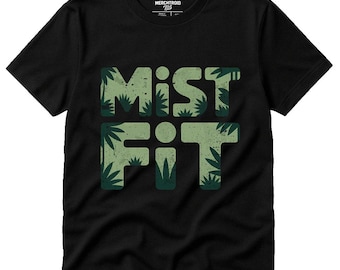 May include: Black t-shirt with the word "Misfit" in green, leaf-patterned letters. The shirt has a crew neck and short sleeves. The brand name "MERCHTROID" is printed at the top.