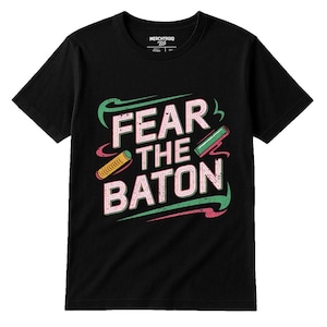 May include: Black t-shirt with the text "FEAR THE BATON" in white, outlined in pink and green. The design includes stylized batons in yellow and green. The shirt has a crew neck and short sleeves.