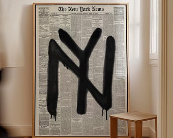 May include: A framed artwork featuring a vintage newspaper background with the text "The New York News" at the top. A large black graffiti-style "NY" is spray-painted across the center. A small wooden side table is next to the artwork.