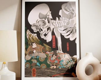 May include: Framed Japanese woodblock print featuring a large skeletal figure looming over two figures in traditional garb. The artwork is predominantly black, white, and shades of brown, green, and red. The print is displayed on a wooden cabinet with a white lamp and vase.