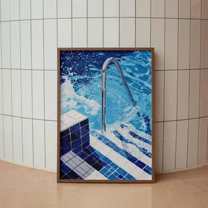 Könnte beinhalten: Ein gerahmter Druck eines Schwimmbeckens mit einer Metallleiter und blauen und weißen Fliesen. Das Wasser ist blau und es gibt weiße Wellen.