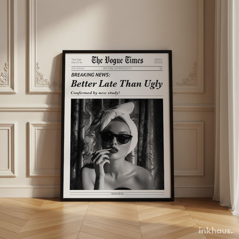 May include: A framed wall art print titled The Vogue Times featuring the headline Breaking News: Better Late Than Ugly. The black and white image shows a person wearing a towel wrap on their head and dark sunglasses, applying lipstick.