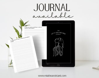May include: A black and white digital tablet displaying a journal cover with the text "The Let It Go & Be Free Journal" and a line drawing of a woman with her head tilted back. The journal cover is on a black background. The tablet is on a white surface with two blank journal pages.
