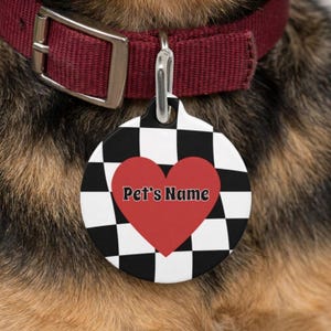May include: A round pet ID tag featuring a black and white checkered pattern with a large red heart in the center. The text Pet's Name is printed in black letters across the red heart. The tag is attached to a dark red collar with a metal buckle.