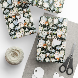 May include: Two rectangular gifts wrapped in paper featuring a repeating pattern of illustrated dogs in black, white, and orange. Each gift is tied with brown twine and includes a white star-shaped or heart-shaped gift tag for labeling.