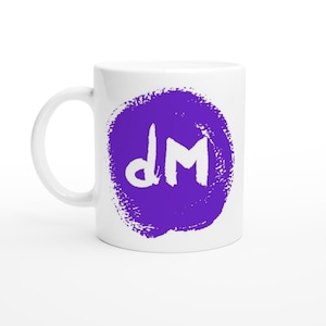 Puede incluir: Taza de café de cerámica blanca con un diseño de círculo morado. El diseño presenta las letras blancas "dM" en un estilo manuscrito. La taza tiene un asa blanca y está sobre un fondo blanco.
