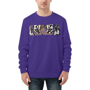 Op de afbeelding: Paarse trui met een grafische print van tijgerogen op de voorkant.