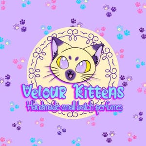 May include: A circular logo featuring a stylized cream-colored kitten head with purple ears and large lavender eyes, centered on a light purple background with scattered paw prints. The text reads Velour Kittens Handmade small batch perfumes.
