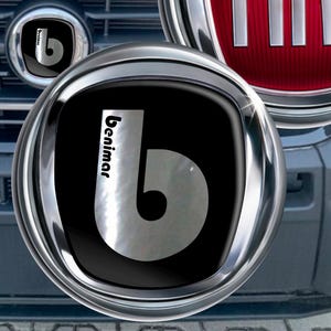 May include: Close-up of a vehicle's front end, featuring a chrome grill and the Fiat logo in a red circle. The Benimar logo is also visible. The vehicle's body is light gray.